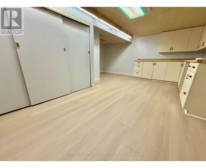 A room with white cupboards and a wooden floor.