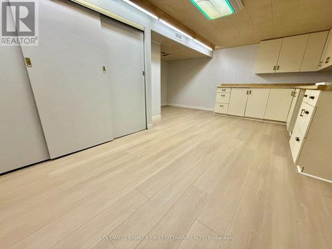 A room with white cupboards and a wooden floor.