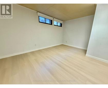 A room with wooden flooring and two windows.