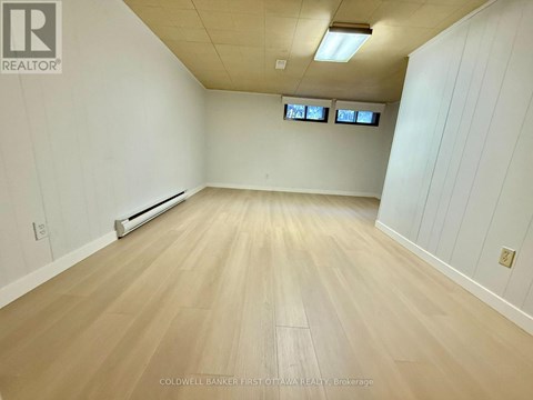 A spacious room with wooden flooring and white walls.