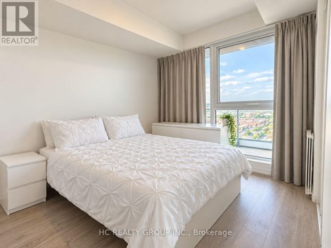 A bedroom with a large bed and a window overlooking a cityscape.