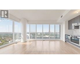 A spacious, well-lit living room with a view of the cityscape outside the large windows.