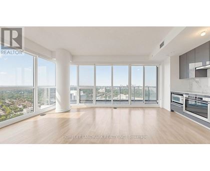 A spacious, well-lit living room with a view of the cityscape outside the large windows.