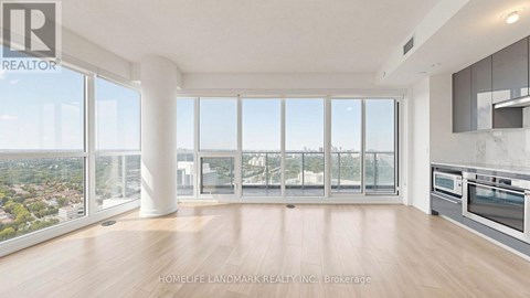A spacious, well-lit living room with a view of the cityscape outside the large windows.