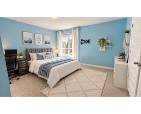 A bedroom with a bed, a desk, and a window.