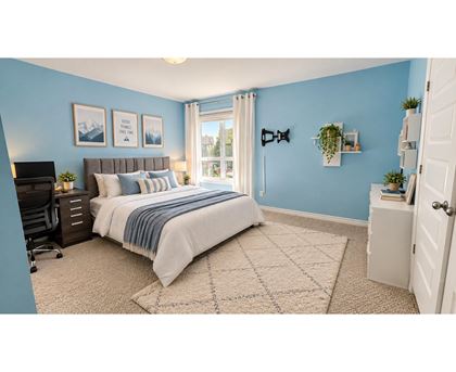 A bedroom with a bed, a desk, and a window.