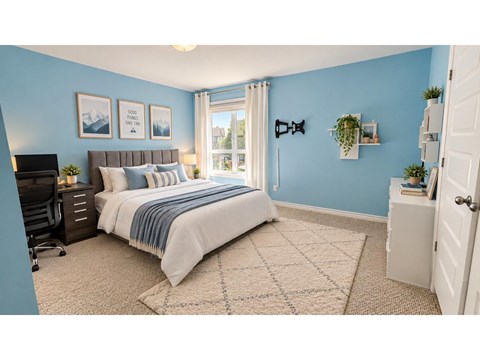 A bedroom with a bed, a desk, and a window.
