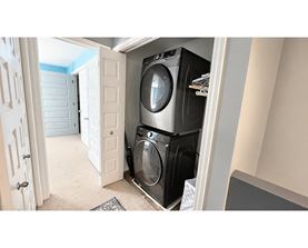 A washing machine is in a small space between a door and a wall.