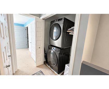 A washing machine is in a small space between a door and a wall.