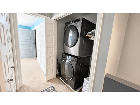 A washing machine is in a small space between a door and a wall.