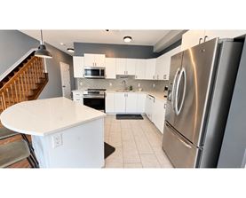 A modern kitchen with a stainless steel refrigerator and white countertops.
