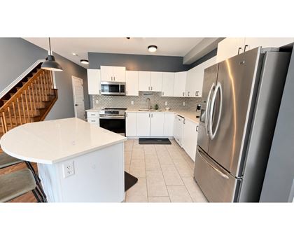 A modern kitchen with a stainless steel refrigerator and white countertops.