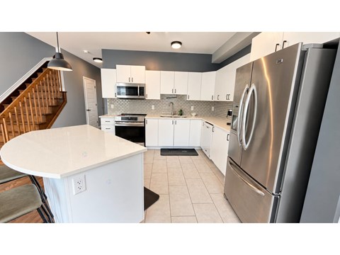 A modern kitchen with a stainless steel refrigerator and white countertops.