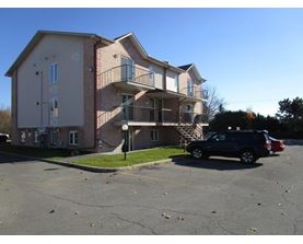 A two-story apartment building with a parking lot in front.