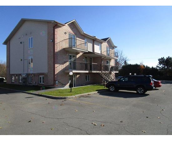 A two-story apartment building with a parking lot in front.