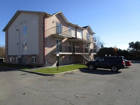 A two-story apartment building with a parking lot in front.