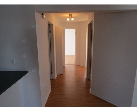 A long hallway with doors on both sides and a light at the end.