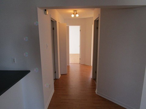 A long hallway with doors on both sides and a light at the end.