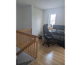 A room with a wooden staircase and a black office chair.