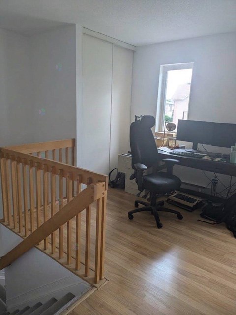 A room with a wooden staircase and a black office chair.