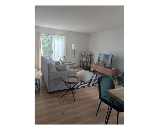 A living room with a grey couch, a black chair, a wooden table, and a television.