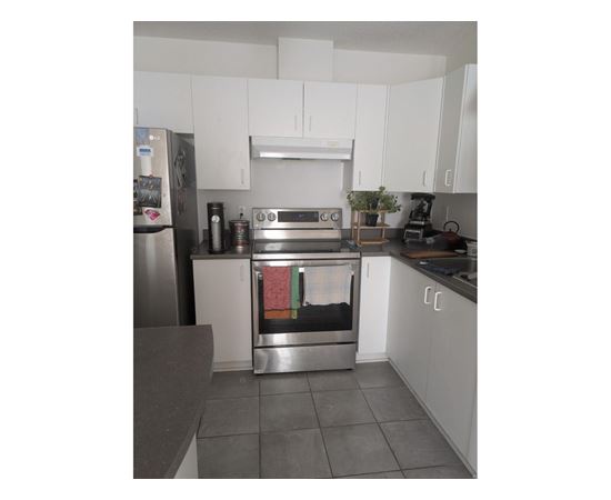 A kitchen with a stainless steel refrigerator and white cabinets.