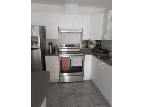 A kitchen with a stainless steel refrigerator and white cabinets.
