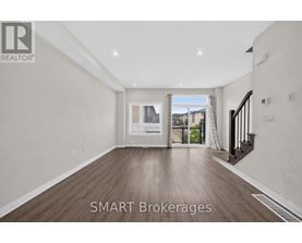 A spacious room with wooden flooring and a view of a cityscape through the window.