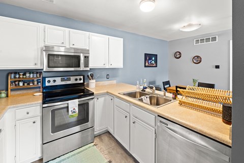 A kitchen with a stove, oven, sink, and cabinets.