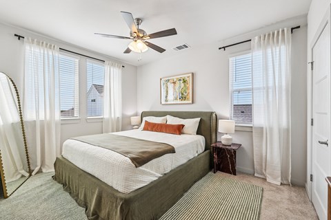A bedroom with a large bed and a ceiling fan.