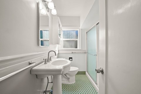 A white sink and toilet in a bathroom with a green and white checkered floor.