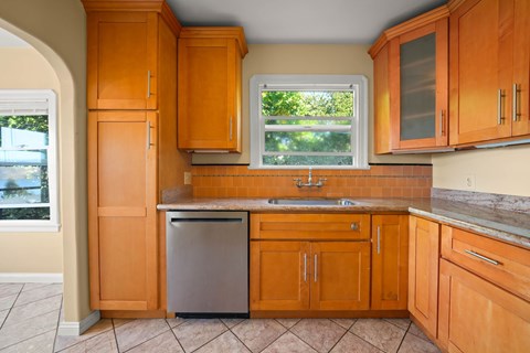 A kitchen with wooden cabinets and a stainless steel dishwasher.