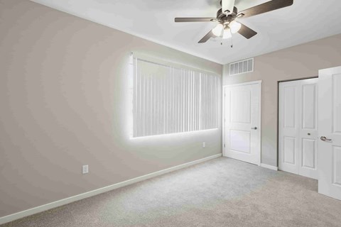 A room with a ceiling fan and two doors.
