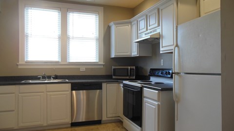A kitchen with white cabinets and a black countertop.