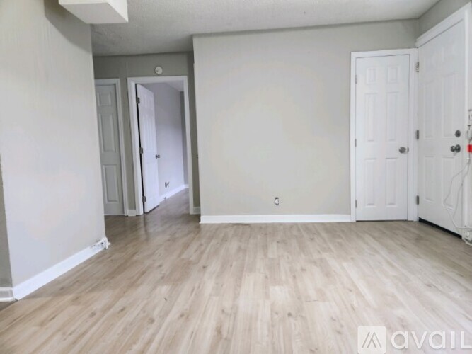 A room with light wood flooring and white walls.