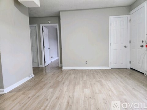 A room with light wood flooring and white walls.