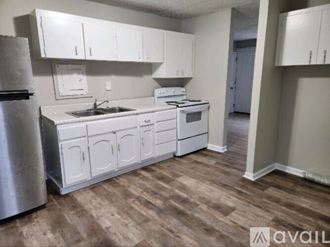 A kitchen with white cabinets and a wooden floor.