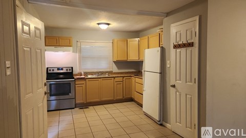 A kitchen with a white refrigerator, wooden cabinets, and a white oven.