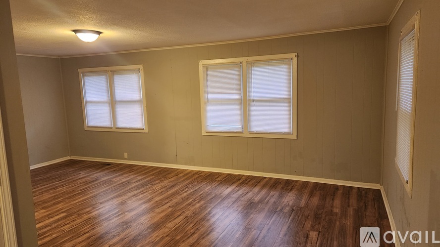 A room with wooden floors and two windows.