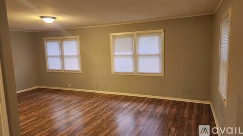 A room with wooden floors and two windows.