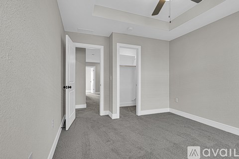 A spacious room with a carpeted floor and a ceiling fan.