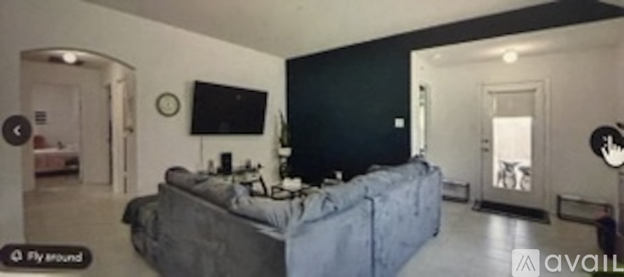 A living room with a grey couch and a flat screen TV mounted on the wall.