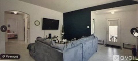 A living room with a grey couch and a flat screen TV mounted on the wall.