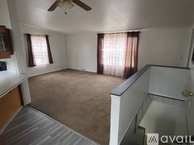 A living room with a ceiling fan and carpeted floor.