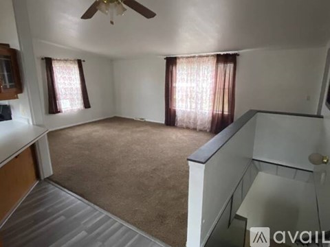 A living room with a ceiling fan and carpeted floor.
