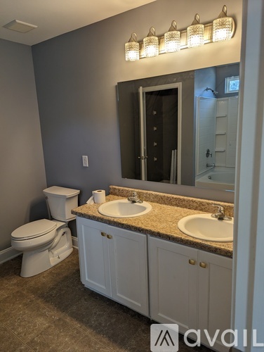 A bathroom with a toilet, sink, and mirror.