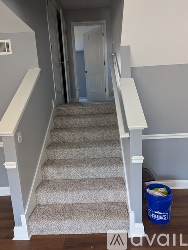 A staircase with a blue bucket labeled "LOWES" on the floor.