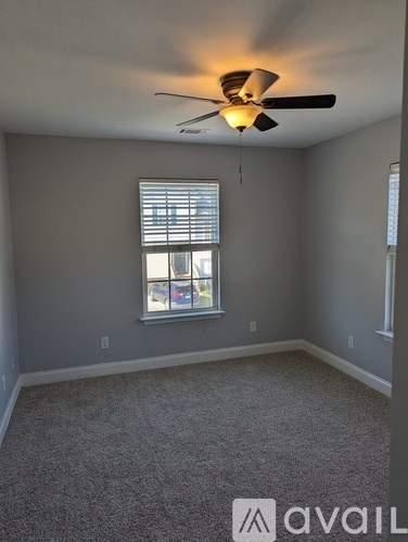 A room with a ceiling fan and a window with blinds.