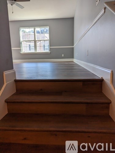 A room with wooden stairs leading to a window.