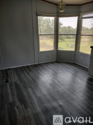 A room with wooden flooring and large windows overlooking a grassy area.